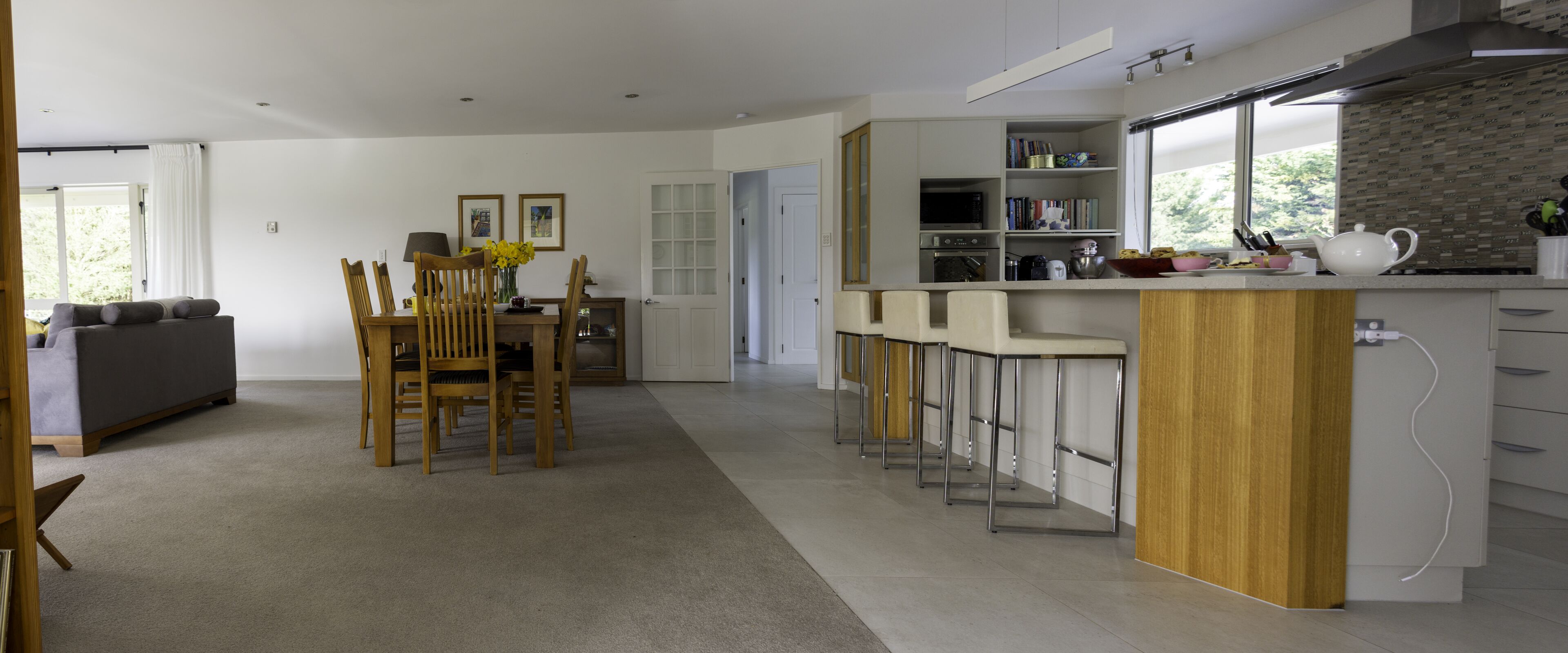 A modern kitchen with a bar area, a dining table with chairs, and a sofa in the living area.