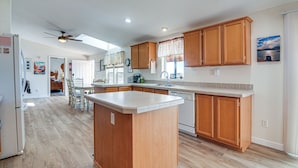 A spacious kitchen with wooden cabinets, a central island, and a dining area with chairs.
