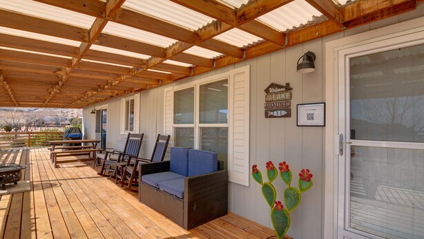 A covered patio with wooden flooring, outdoor furniture, and a cactus decoration.