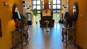 Een ruime lobby met een grote open haard, sierlijke kroonluchters en een hoge plafond.