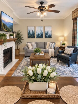 A living room with a fireplace, a sofa, a coffee table, and a ceiling fan.