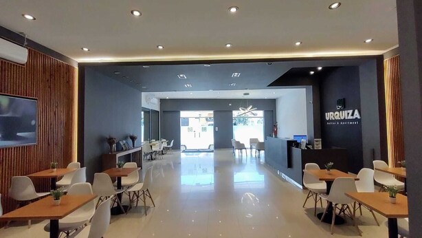 A modern hotel lobby with a reception desk, seating area, and a view of the street. - Urquiza Suites Salta (Salta)