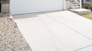 A two-story house with a white garage, a small porch, and a stone accent wall.