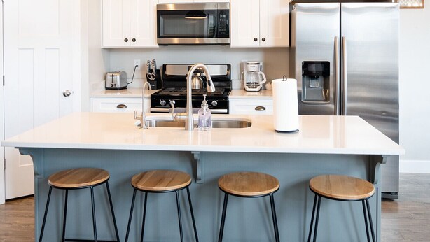 A modern kitchen with white cabinets, stainless steel appliances, and a central island with stools.