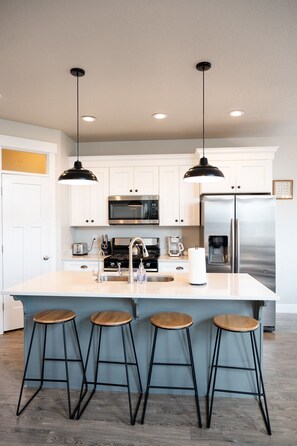 A modern kitchen with white cabinets, stainless steel appliances, and a central island with stools. - ⭐️Sleeps 10⭐️ Pool and workout room access⭐️ (Herriman)