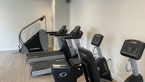 A home gym with a treadmill, elliptical, and stationary bike.