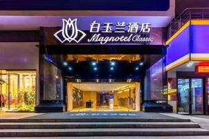 Exterior de un hotel con un cartel llamativo, un acceso cubierto y una fachada bien iluminada.