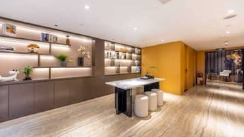 A modern interior with a marble floor, a central table, and a seating area with a yellow accent wall.