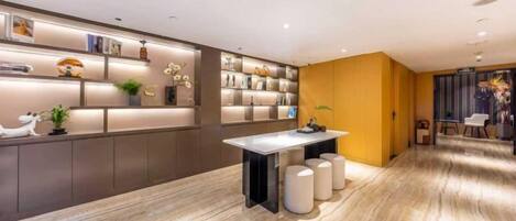 A modern interior with a marble floor, a central table, and a seating area with a yellow accent wall.