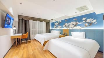 A hotel room with two beds, a desk, a chair, a TV, and a decorative wall.