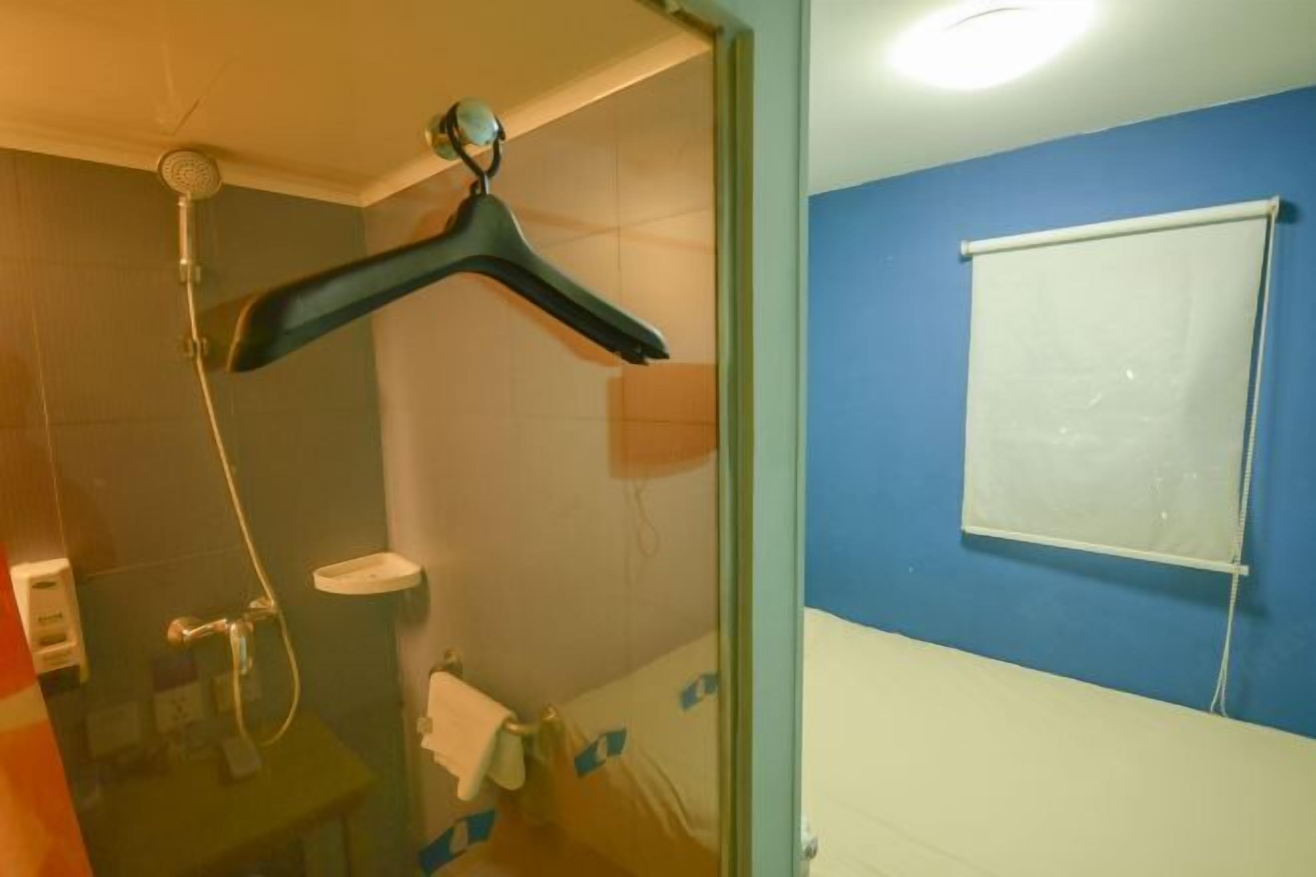 Un baño con ducha, inodoro y ventana con persiana.