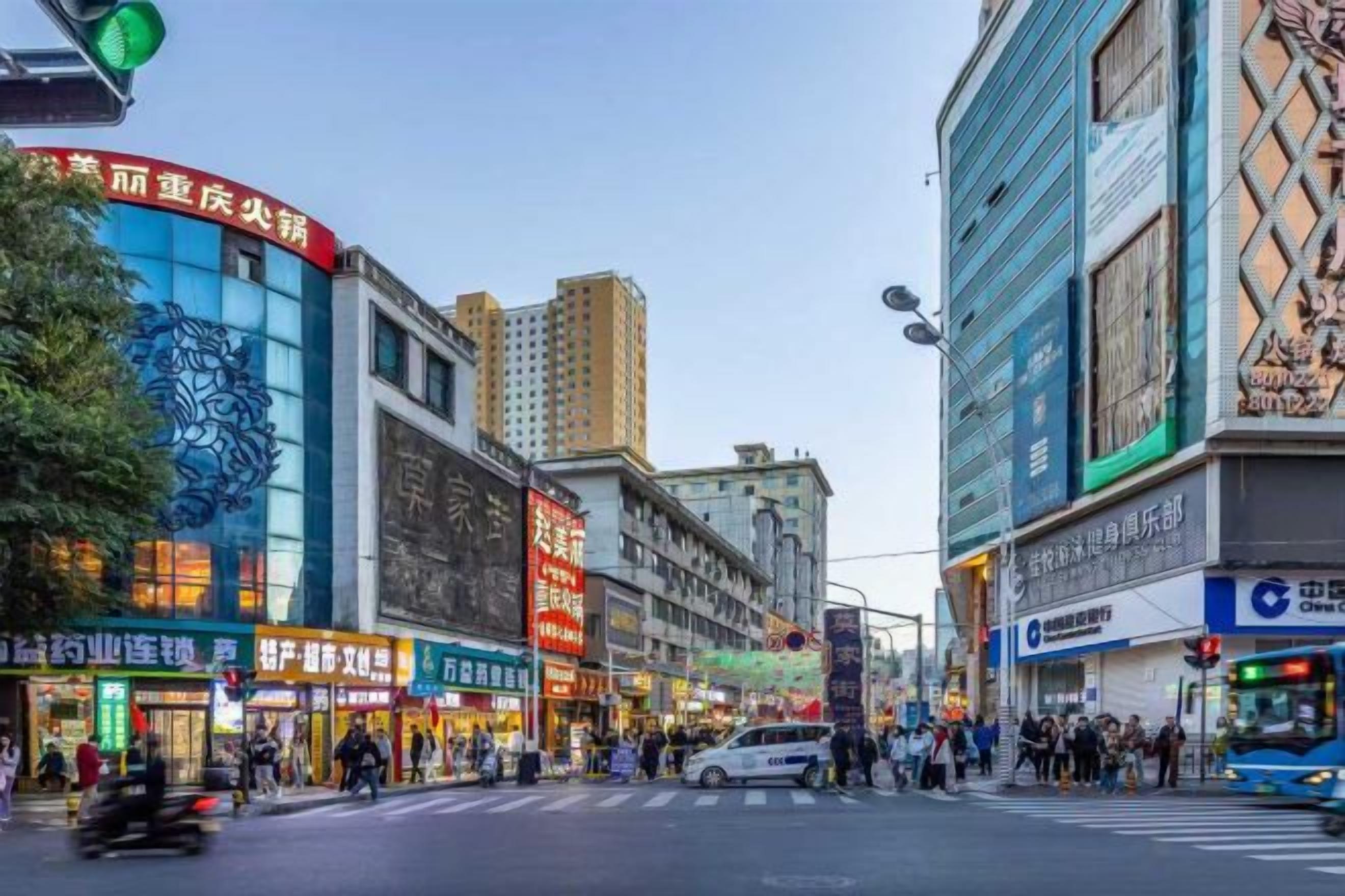 A busy urban street with commercial buildings, shops, and pedestrians.