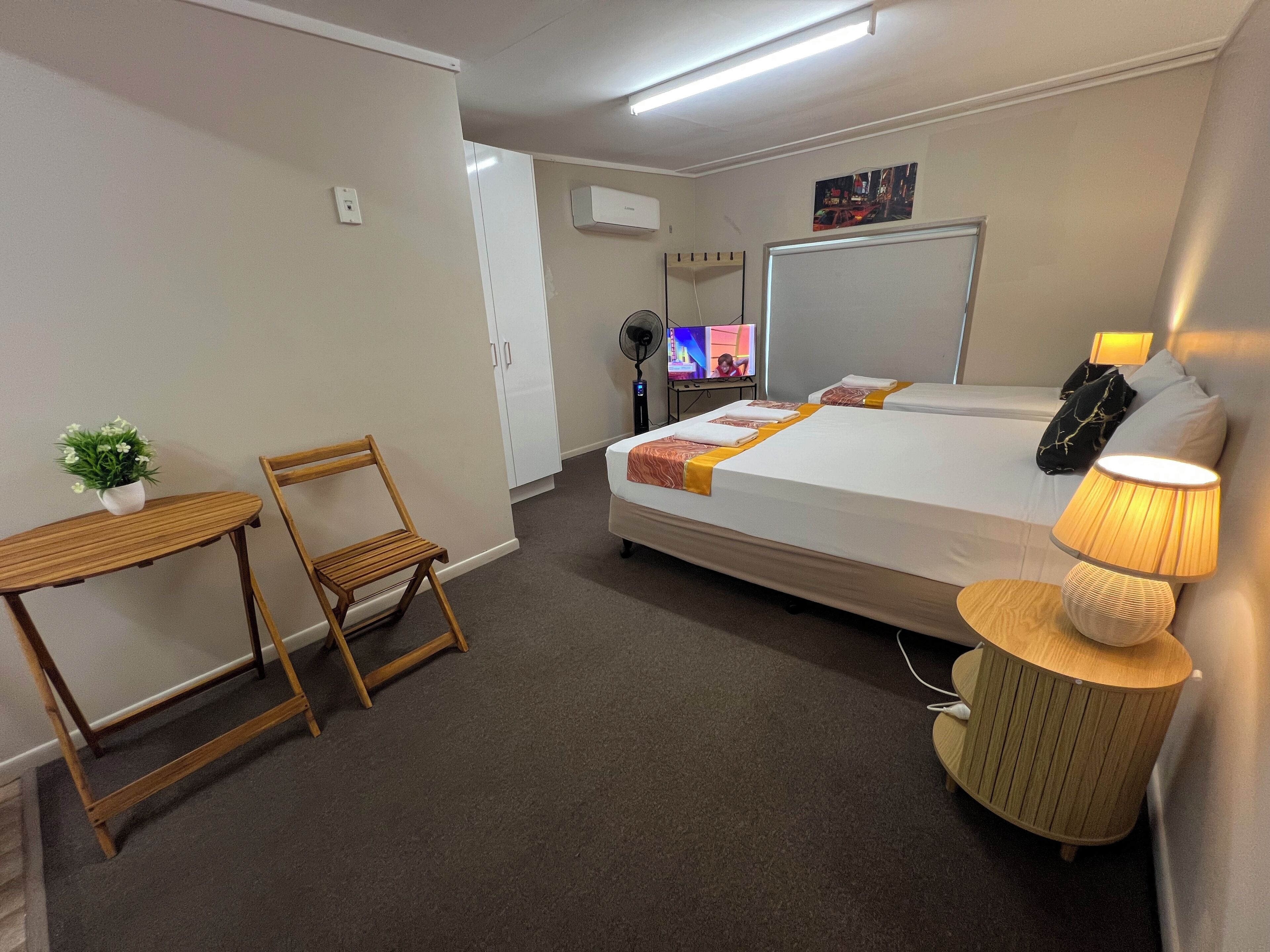 A hotel room with a bed, bedside table, chair, lamp, and a TV.