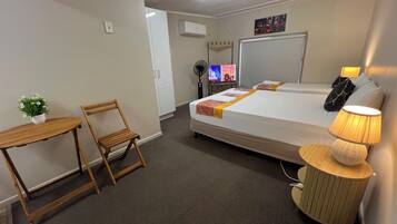 A hotel room with a bed, bedside table, chair, lamp, and a TV.