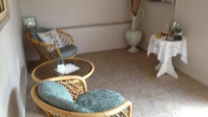 Quarto com mobiliário de vime, uma pequena mesa com um vaso e um mural na parede.