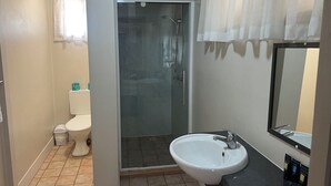 Casa de banho com sanita, chuveiro e lavatório.