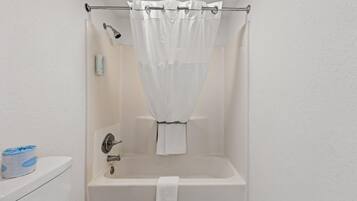 Et badeværelse med badekar, bruseforhæng, et håndklæde og en toiletpapirholder.