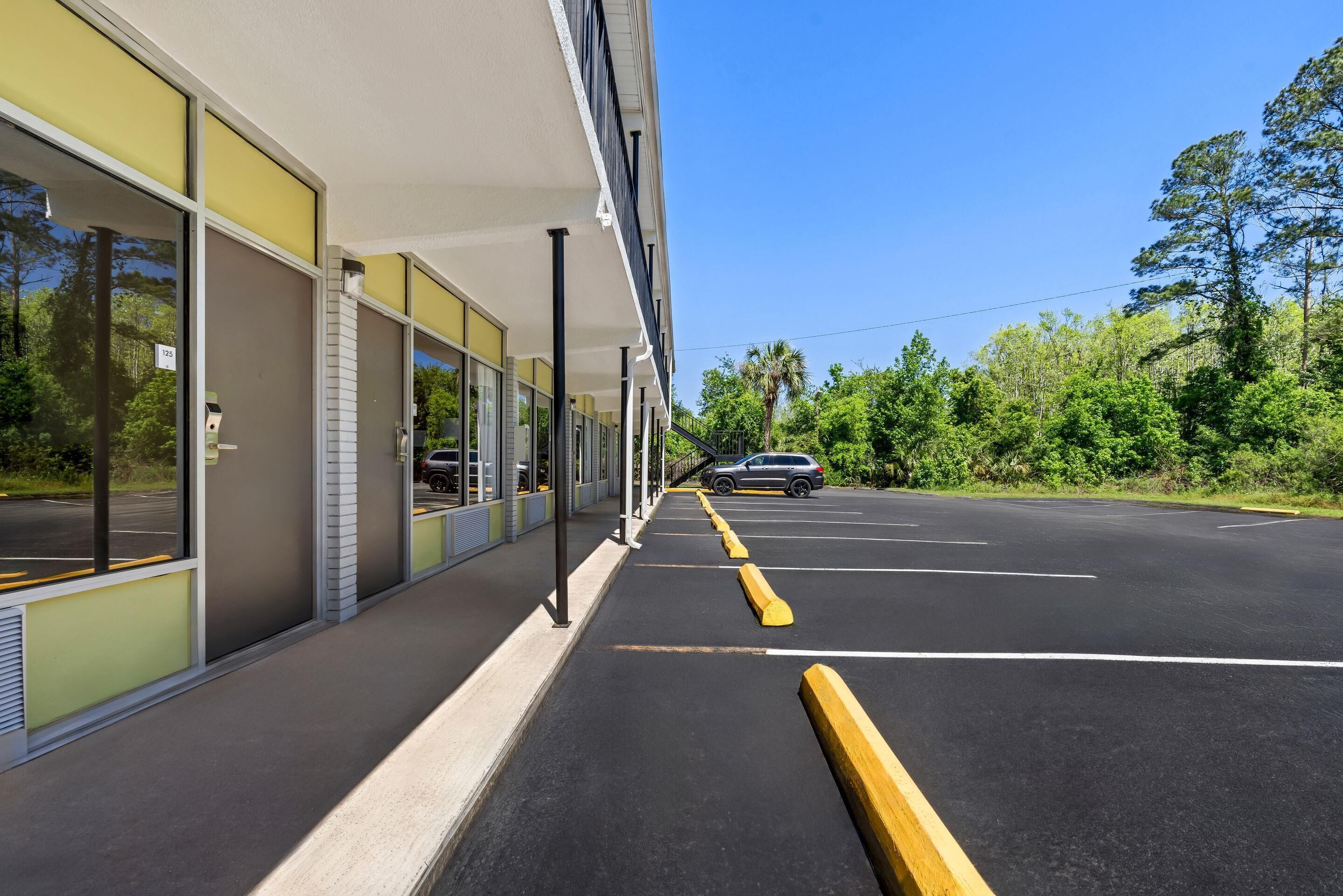 A modern building with large windows and a parking lot.