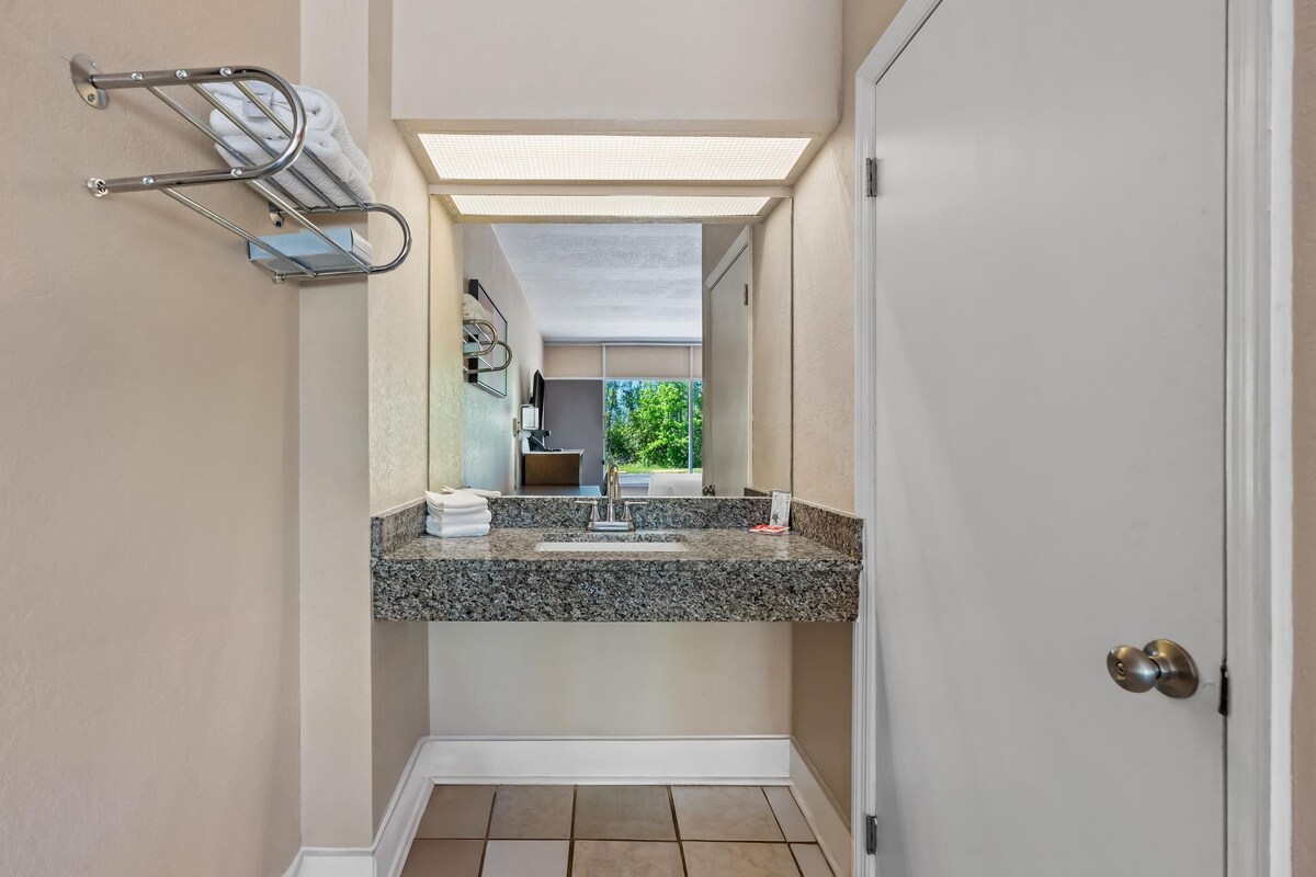 A narrow bathroom with a vanity, a towel rack, and a door.