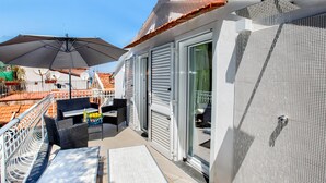 Een balkon met buitenmeubilair, een schuifpui en een structuurwand.
