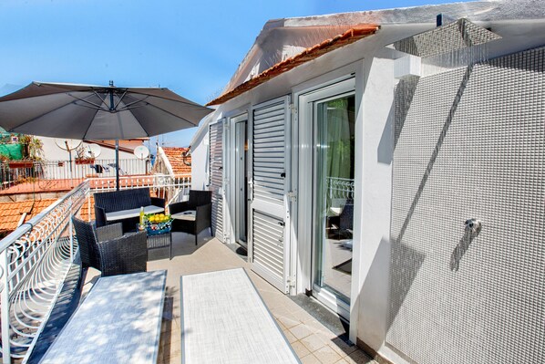 Un balcon avec des meubles d’extérieur, une porte-fenêtre coulissante et un mur à texture.