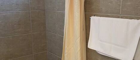 A bathroom with a shower curtain, a toilet, and a towel rack.