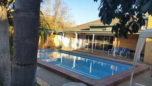 Une piscine dotée d’une zone abritée et de chaises longues.