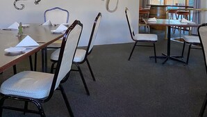 Un espace repas avec des tables et des chaises, des œuvres d’art décoratives sur les murs et une vue sur l’extérieur.