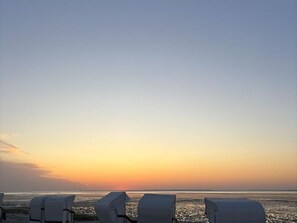 Une vue sur la plage, avec des chaises longues et un coucher de soleil.