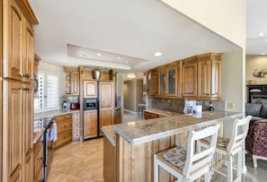 Una cocina amplia con armarios de madera, encimera de granito y una isla central con taburetes de bar.
