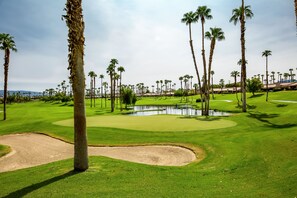 A golf course with sand bunkers, palm trees, and a pond. - Waterfront Desert Escape, Waterfalls, Membership Access (Palm Desert)
