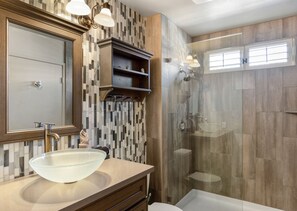 A modern bathroom with a glass sink, a walk-in shower, and a vanity with a mirror and cabinet. - Waterfront Desert Escape, Waterfalls, Membership Access (Palm Desert)