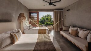 Quarto moderno com cama grande, sofá, rede e vista para o verde lá fora.