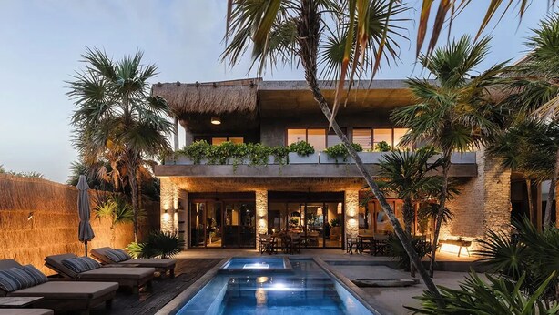 Uma casa moderna com piscina, área de estar externa e plantas tropicais.