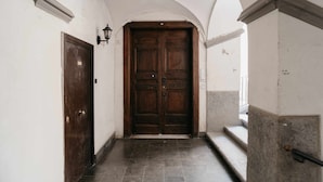 A hallway with a wooden double door, white walls, and a tiled floor. - Nilo – Historic Apartment with Patio by Casa N (Napoli)