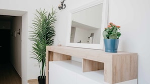 A modern bathroom with a wooden vanity, a large mirror, a potted plant, and a blue vase with flowers. - Nilo – Historic Apartment with Patio by Casa N (Napoli)
