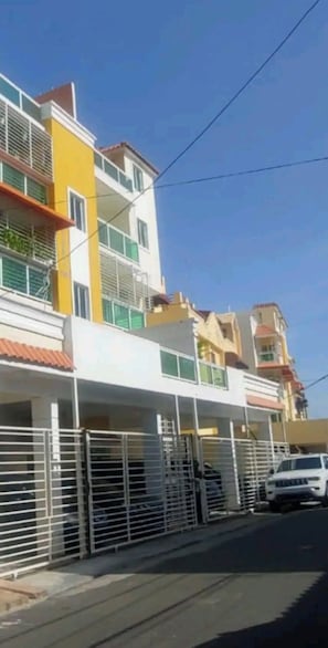 Um edifício residencial com várias andares, varandas e entrada com portão.