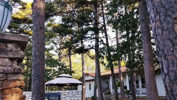 A stone wall, a wooden bench with "Eureka Springs Transit" engraved, and a Tuscan Manor sign in the background. - Tuscan Manor (Eureka Springs)
