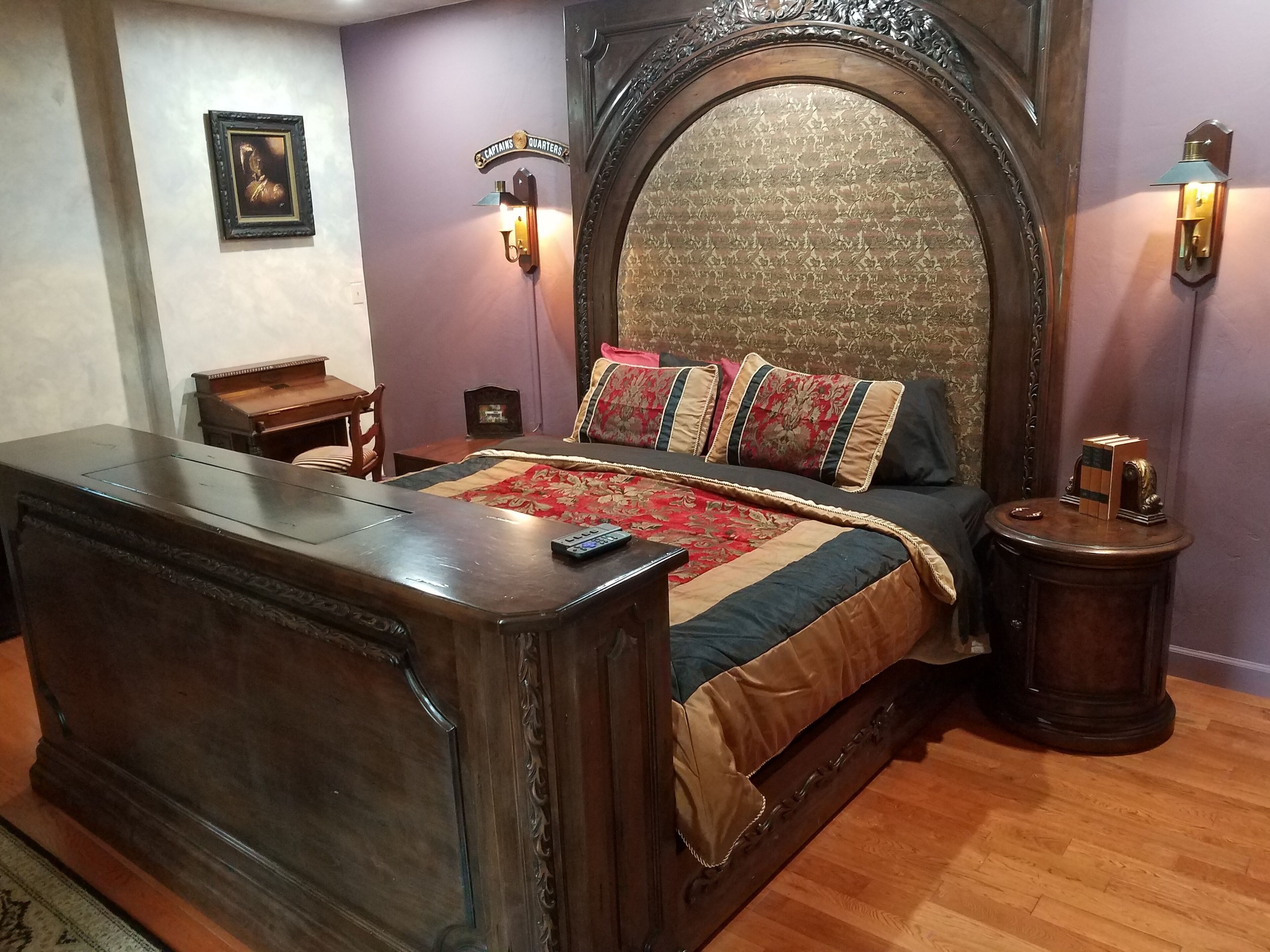 Una camera da letto con un letto grande, una cassettiera in legno, un comodino e una lampada fissata al muro.