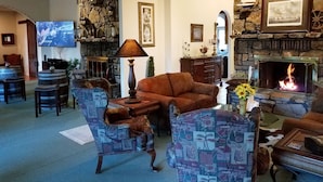 A cozy living room with a stone fireplace, comfortable seating, and a television. - Tuscan Manor (Eureka Springs)