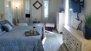 A bedroom with a large bed, a dresser, a TV, and a window with curtains. - Tuscan Manor (Eureka Springs)
