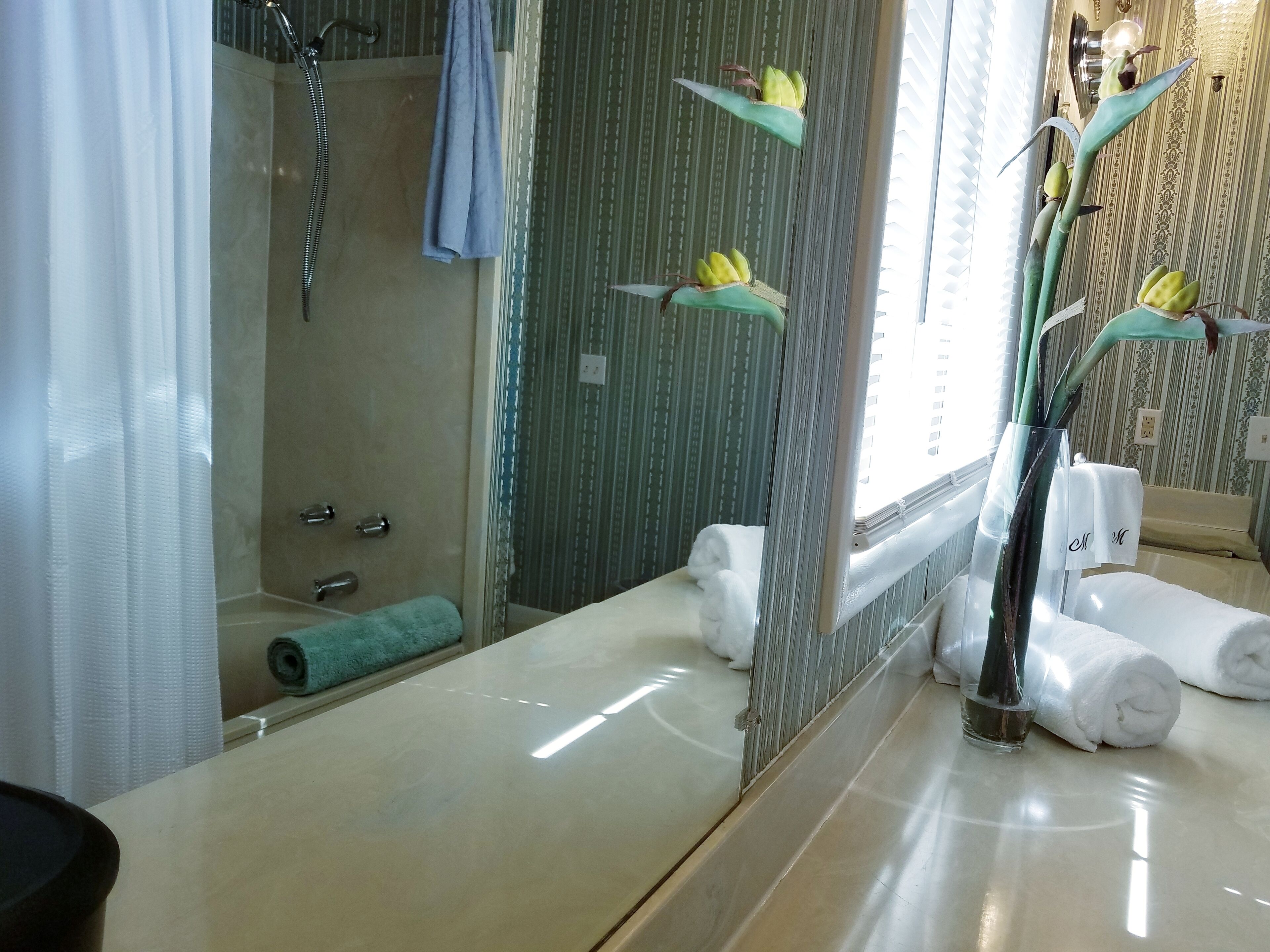 Ein Badezimmer mit großem Spiegel, Badewanne, Dusche und Toilette.