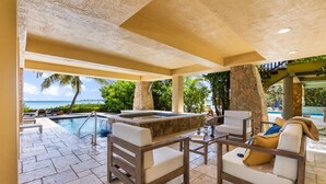 Un espace de détente extérieur comprenant un jacuzzi, des sièges et une vue sur l’océan.