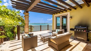 A covered patio with wicker furniture, a grill, and a view of the sea. - ✦Unwind on your Oceanedge villa on Seapalm island✦ (Little Conch Key)