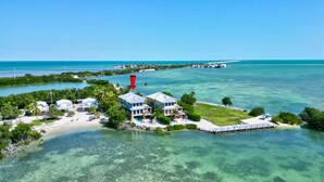An aerial view of a coastal property with multiple buildings, clear turquoise waters, and a pier extending into the sea. - ✦Unwind on your Oceanedge villa on Seapalm island✦ (Little Conch Key)