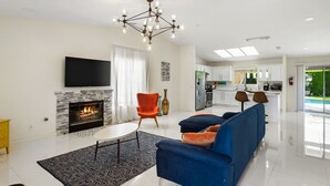 A modern living room with a fireplace, a blue sofa, and a flat-screen TV.