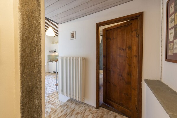 A hallway with a wooden door, a radiator, and a hanging light fixture.