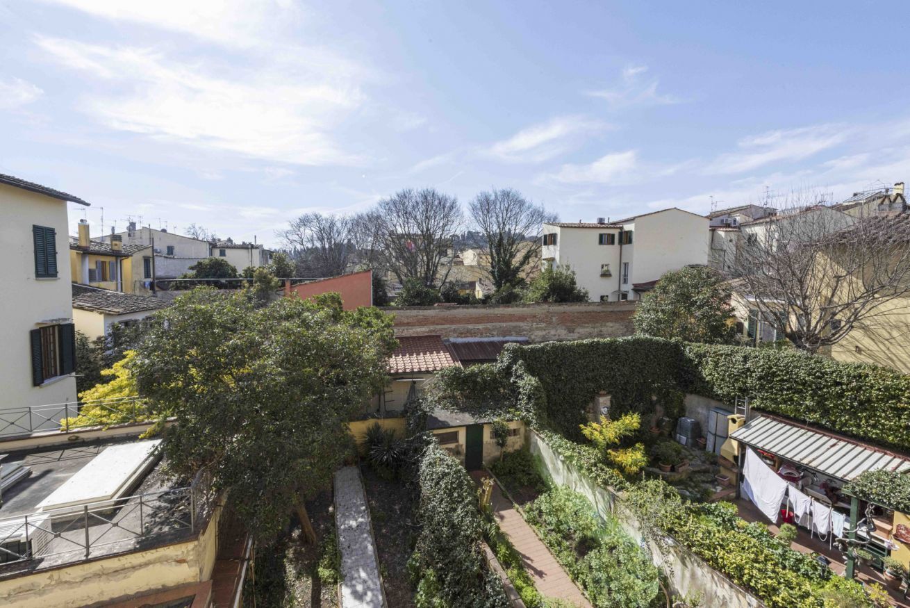 A residential courtyard with buildings, a pathway, and greenery.