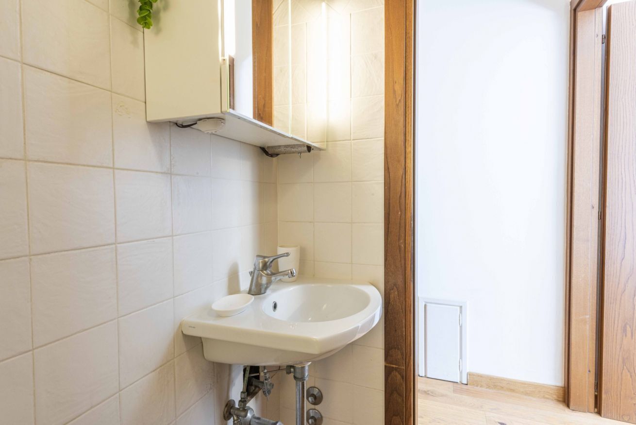 A bathroom with a white sink, a mirror, and a wooden door.