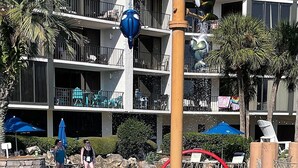 Een waterpark met een zwembad, glijbanen en een meerlaags gebouw op de achtergrond.